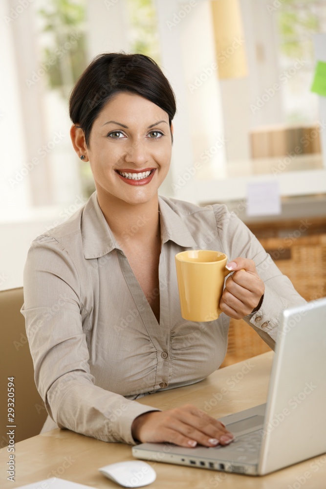 Young woman drinking tea at desk