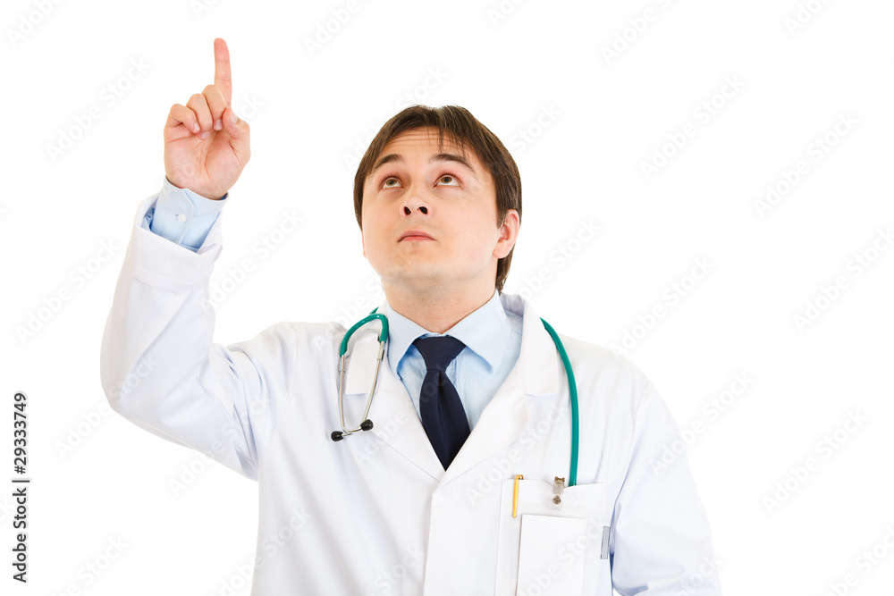 Serious young medical doctor pointing finger up isolated Serious young medical doctor pointing finger up isolated