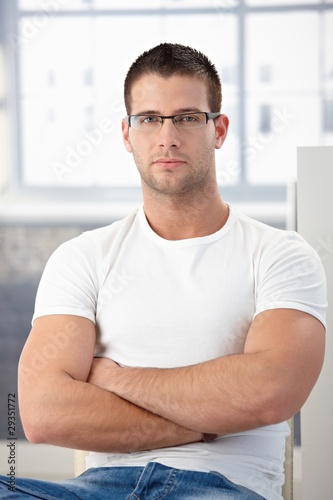 Sporty man wearing glasses sitting arms crossed