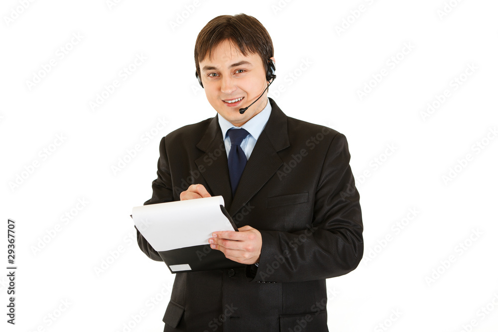 Smiling businessman with headset making notes in document Smiling businessman with headset making notes in document