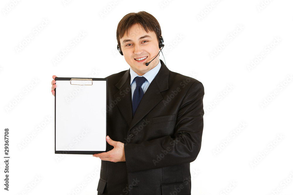 Smiling young businessman with headset holding blank clipboard Smiling young businessman with headset holding blank clipboard