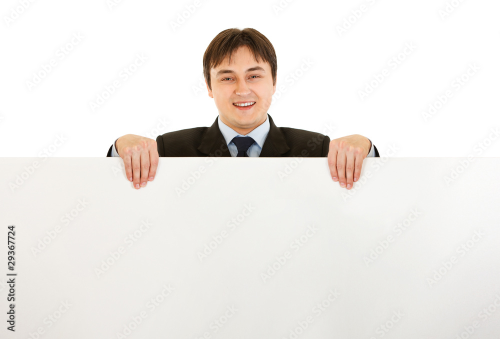 Smiling modern businessman holding blank billboard Smiling modern businessman holding blank billboard