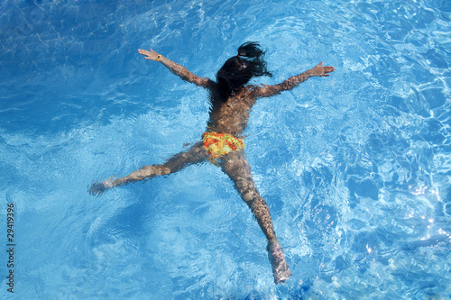 Little girl swimming on her belly in pool