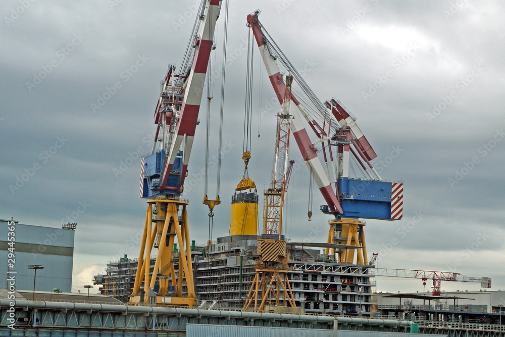cranes during the construction of an ocean liner in a shipyard