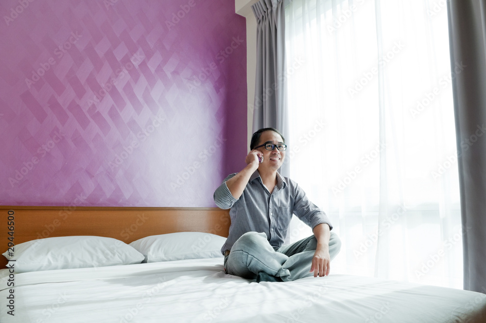 Happy young man speaking on cellphone in bedroom Happy young man speaking on cellphone in bedroom