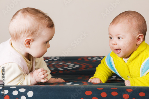 Two babies crawling on a sofa photo