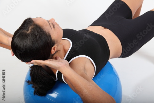 Fitness workout by young woman using exercise ball