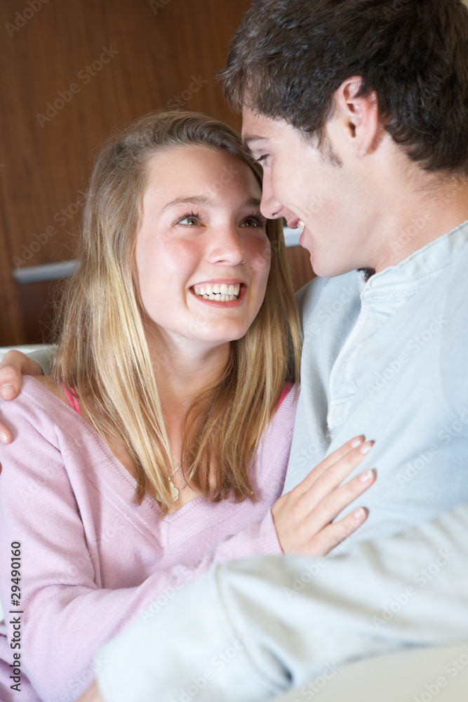 Romantic Teenage Couple Sitting On Sofa At Home Together