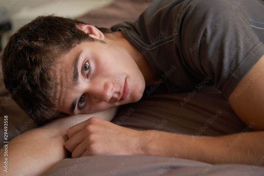Depressed Teenage Boy Lying In Bedroom Depressed Teenage Boy Lying In Bedroom