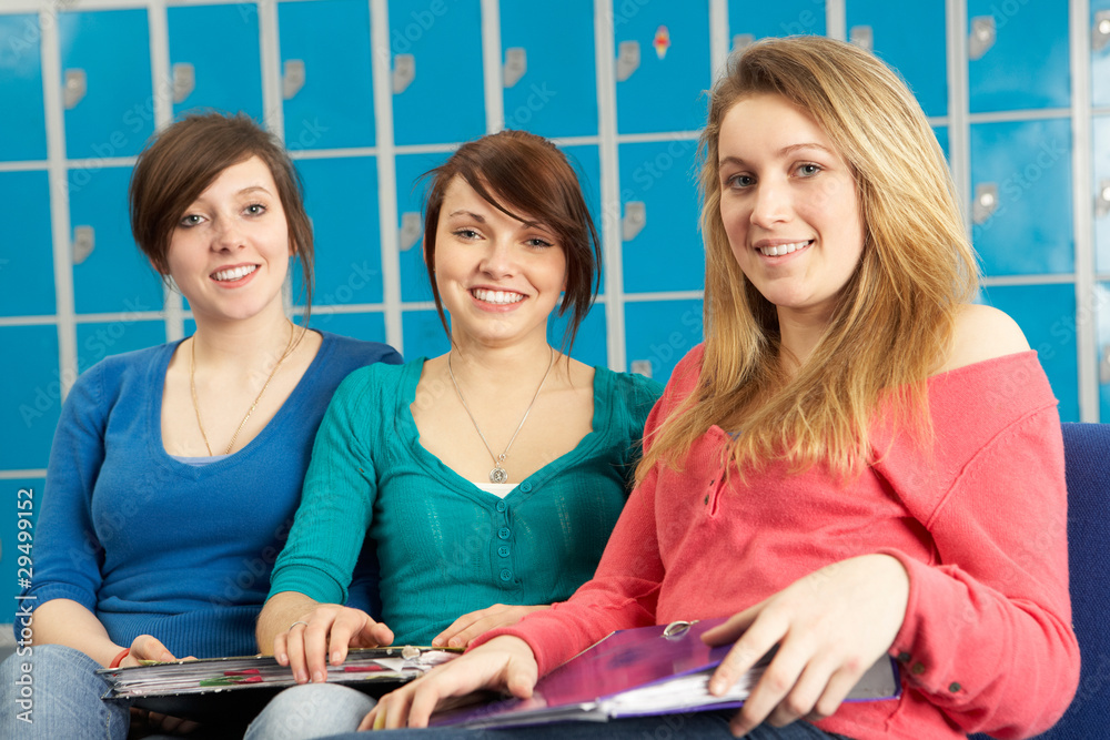 Female Teenage Students Relaxing By Lockers In School Female Teenage Students Relaxing By Lockers In School