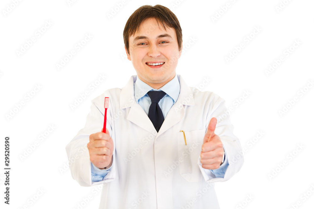 Dentist holding toothbrush and showing thumbs up gesture Dentist holding toothbrush and showing thumbs up gesture