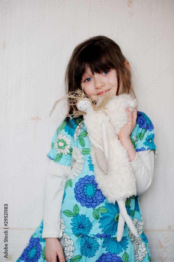 Adorable little girl in bright blue dress hugs her toy angel Adorable little girl in bright blue dress hugs her toy angel