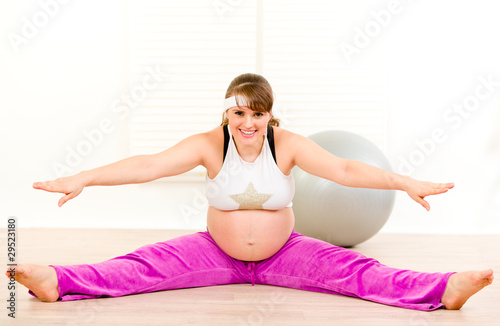 Smiling beautiful pregnant woman doing stretching exercises .