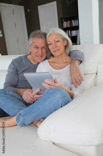 Senior couple sitting in sofa with electronic tablet © goodluz