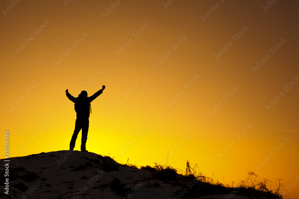 Szczęśliwy mężczyzna na szczycie góry o zachodzie słońca