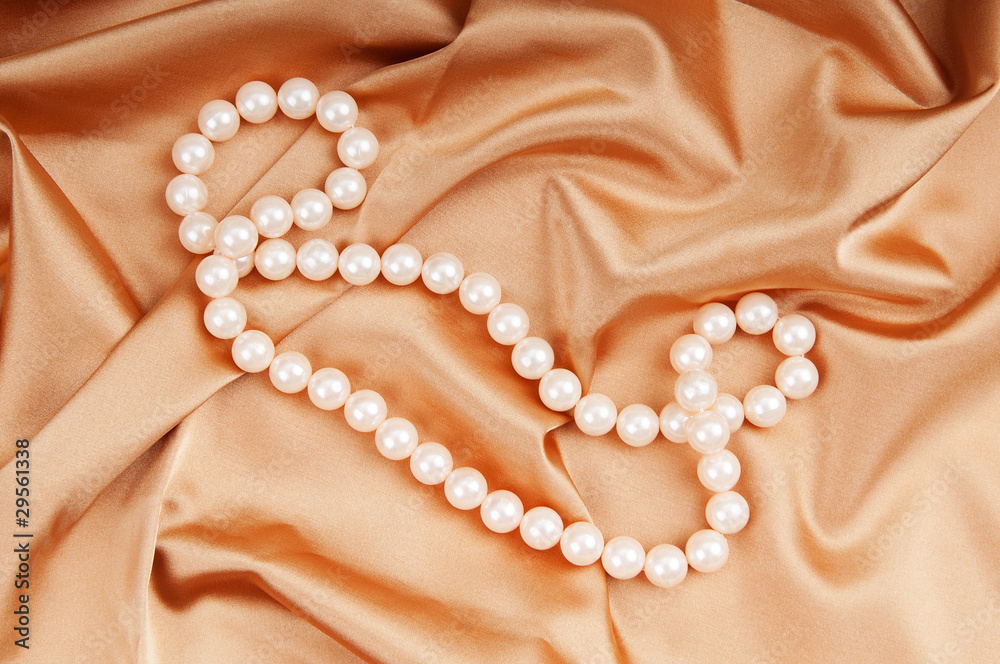 Pearl necklace on the bright satin background