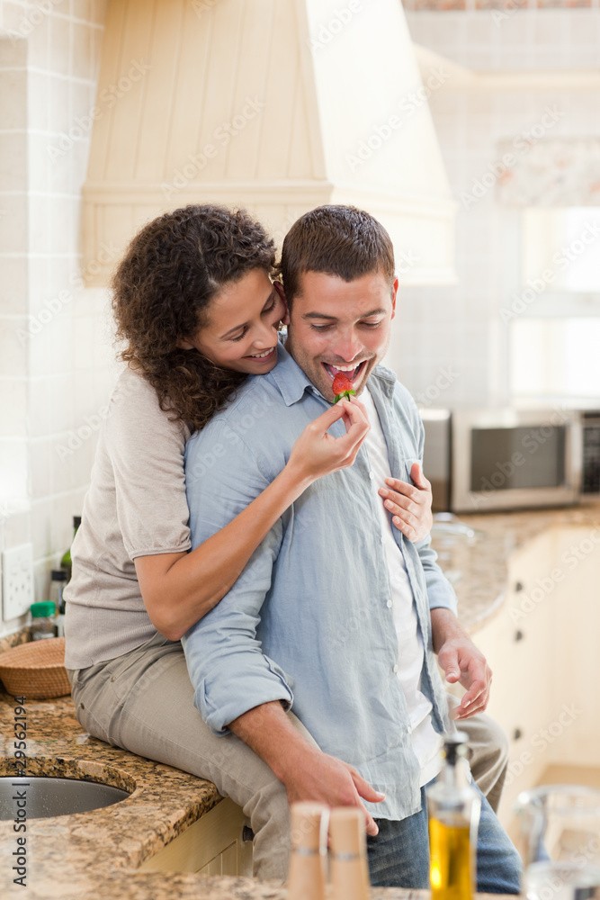 Lovers eating a strawberry in their kitchen