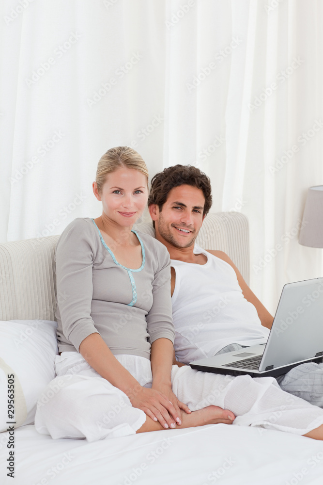 Adorable couple looking at their laptop on the bed Adorable couple looking at their laptop on the bed