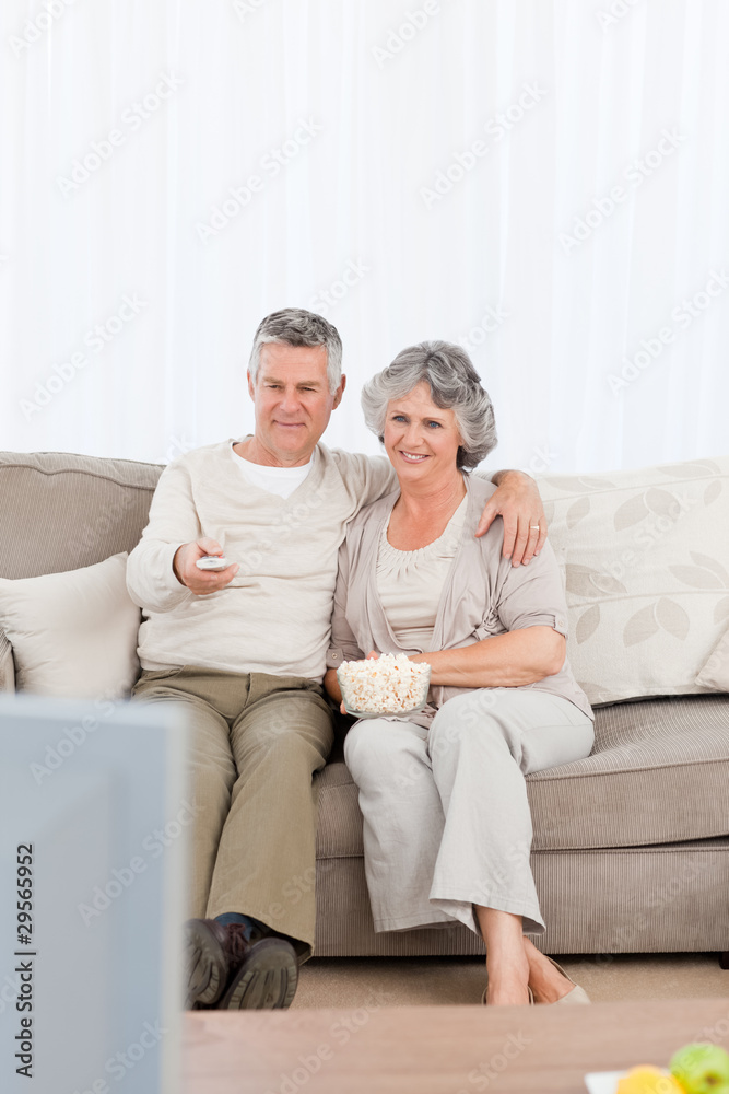 Mature couple watching tv in their living room Mature couple watching tv in their living room