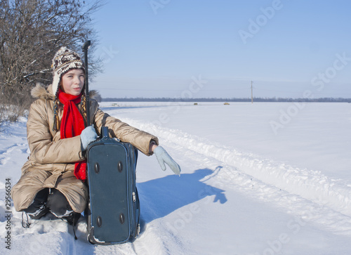 Teen girl with a suitcase outdoors at winter time