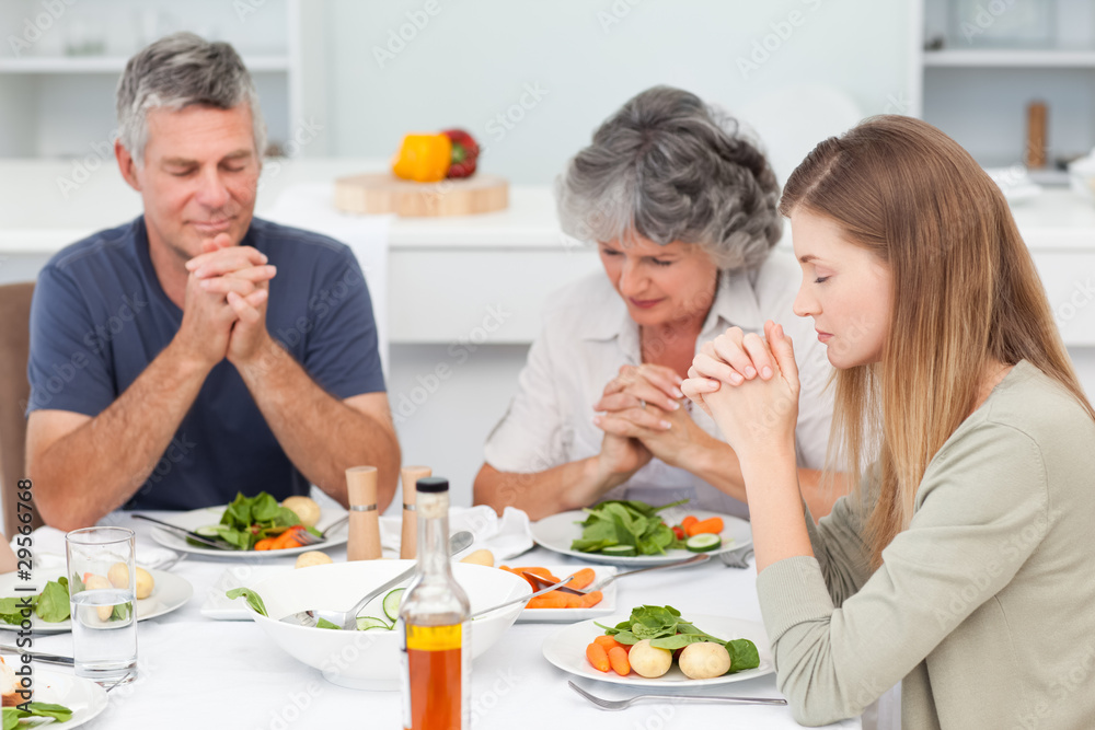 Adorable family praying at the table
