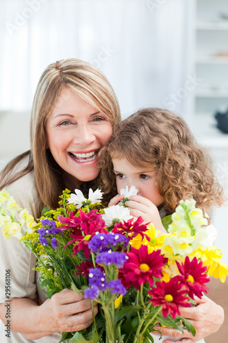 Little girl smelling flowers while her grandmother is smilling © WavebreakMediaMicro