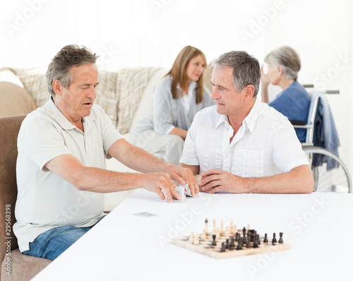 Men playing cards while their wifes are talking