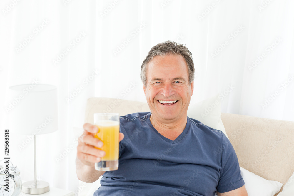 Retired man looking at the camera while he is drinking oranje ju Retired man looking at the camera while he is drinking oranje ju