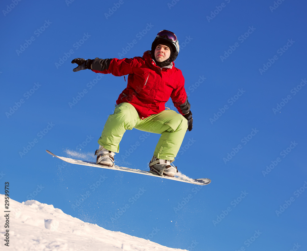 Snowboarder jumping through air with blue sky in background Snowboarder jumping through air with blue sky in background