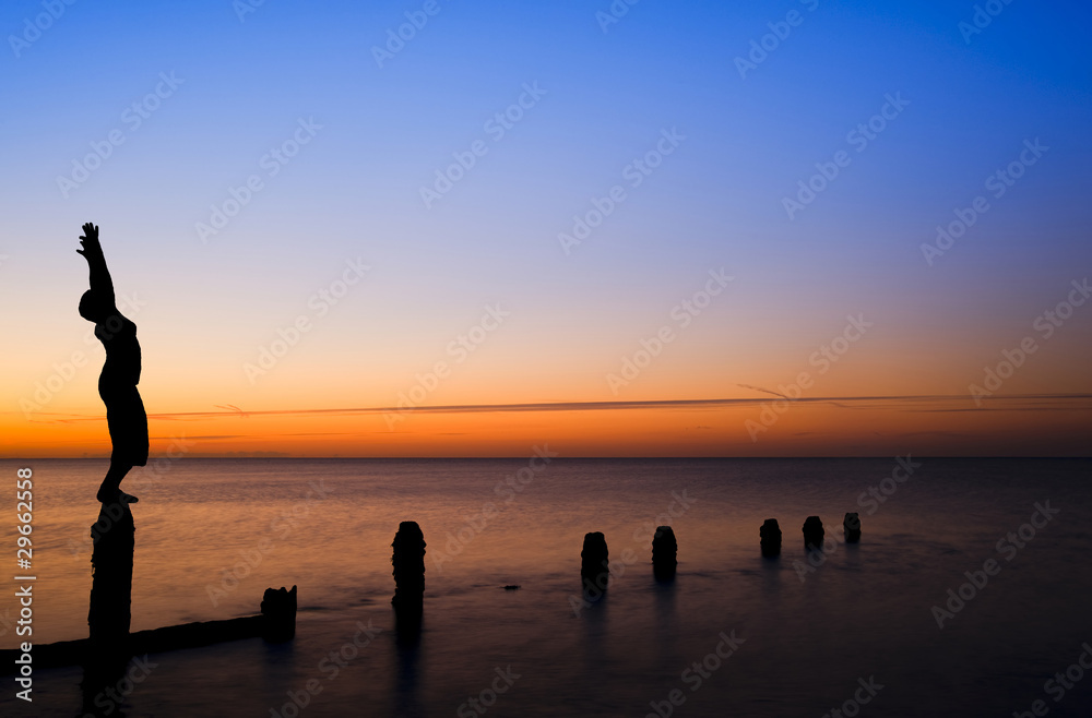 Fototapeta premium Silhouette of woman stretching doing yoga on beach