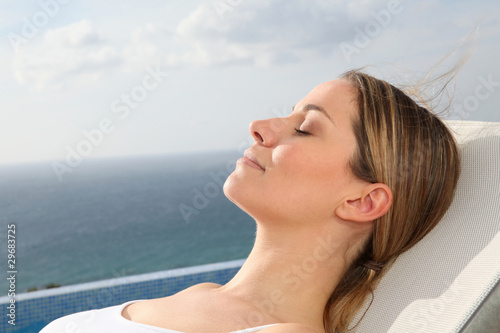 Woman relaxing in deckchair by swimming-pool