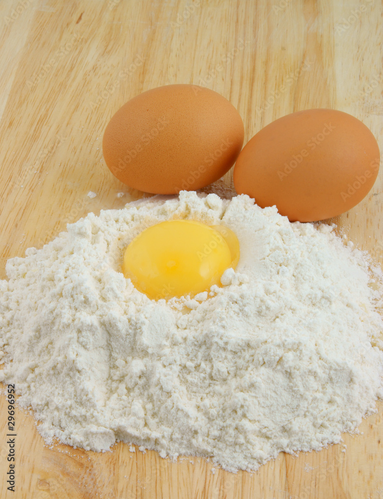 Egg yolk on flour on wooden background