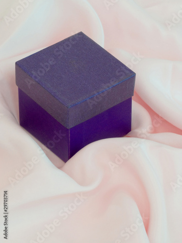 Closeup of closed purple gift box on pink silk