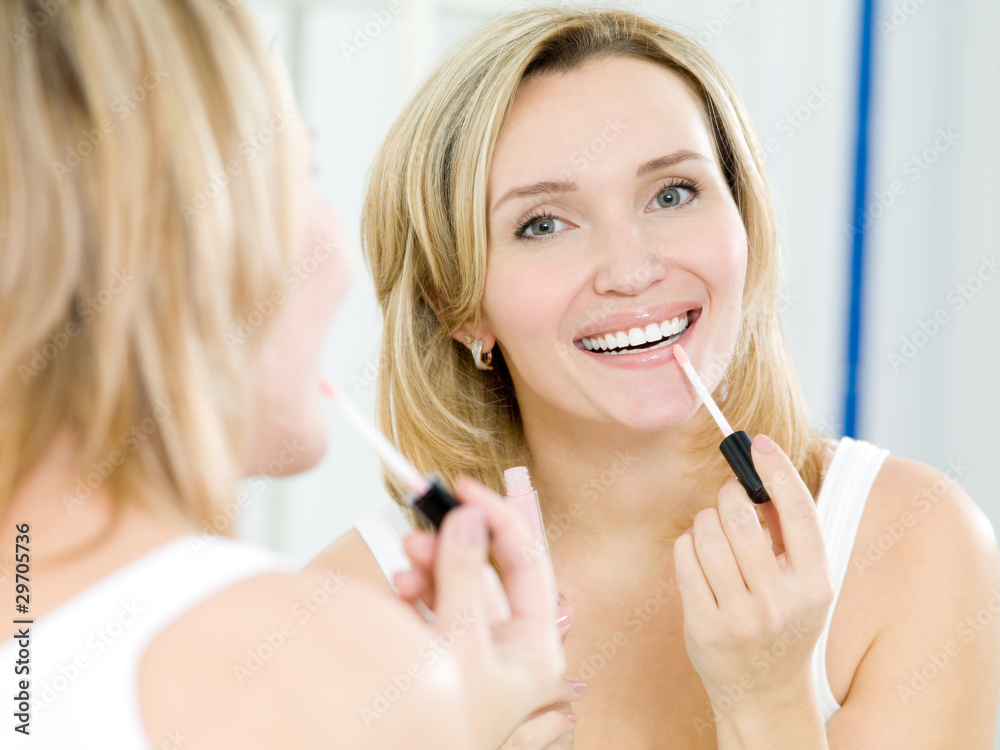 beautiful young girl puts a lip gloss foto de Stock Adobe Stock