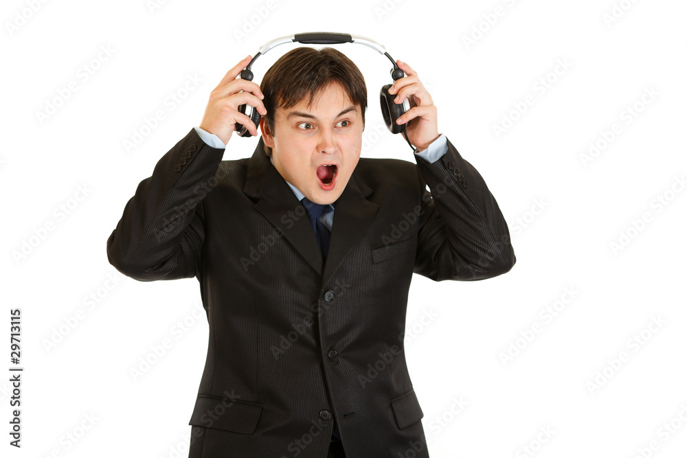 Shocked modern businessman removes headphones Shocked modern businessman removes headphones