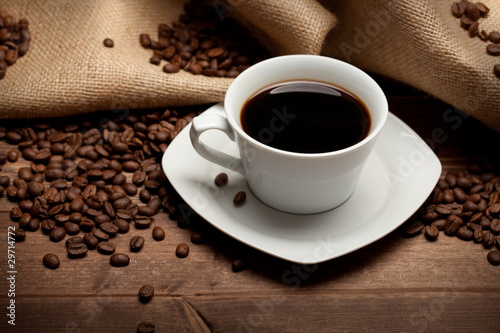 Cup of coffee and beans on jute background