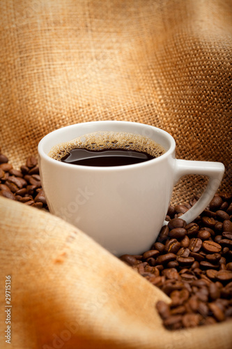 Coffee cup and beans on jute background