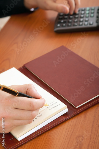 Businessman writing on agenda and using a calculator