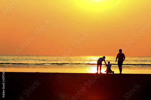 Silhouette image of father child by the sea shore, sunset .