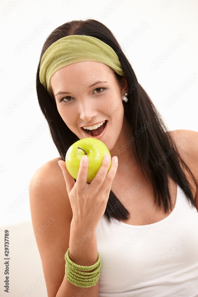 Happy young woman biting apple
