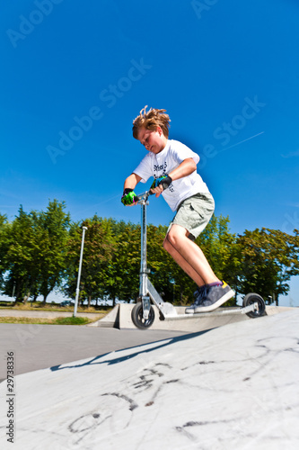 boy has fun at the skate park with his scooter
