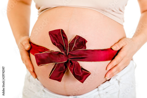 Pregnant woman with red ribbon on belly. Close-up.