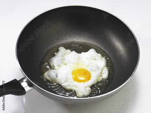 Fried egg with oil in a hot pan.