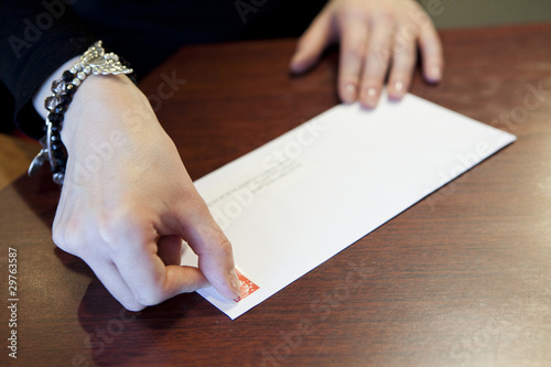 mains de femmes qui timbrent une lettre