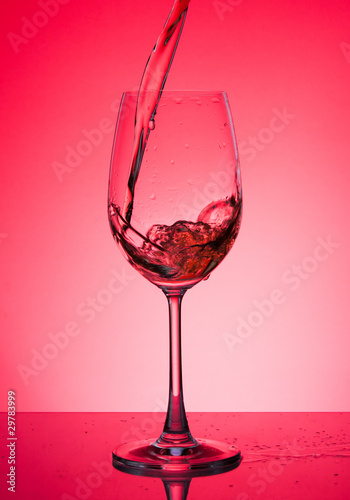 Glass with rose wine on a red background