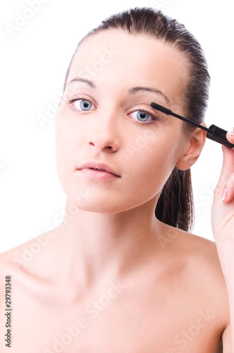 woman is applying mascara on her face