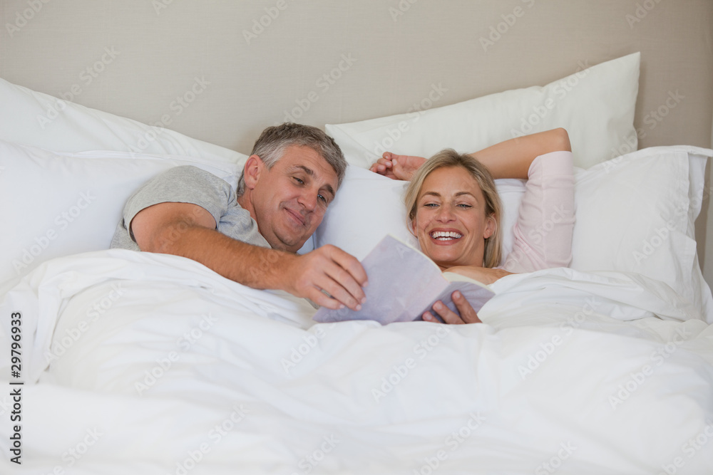 Couple reading a book in their bed Couple reading a book in their bed