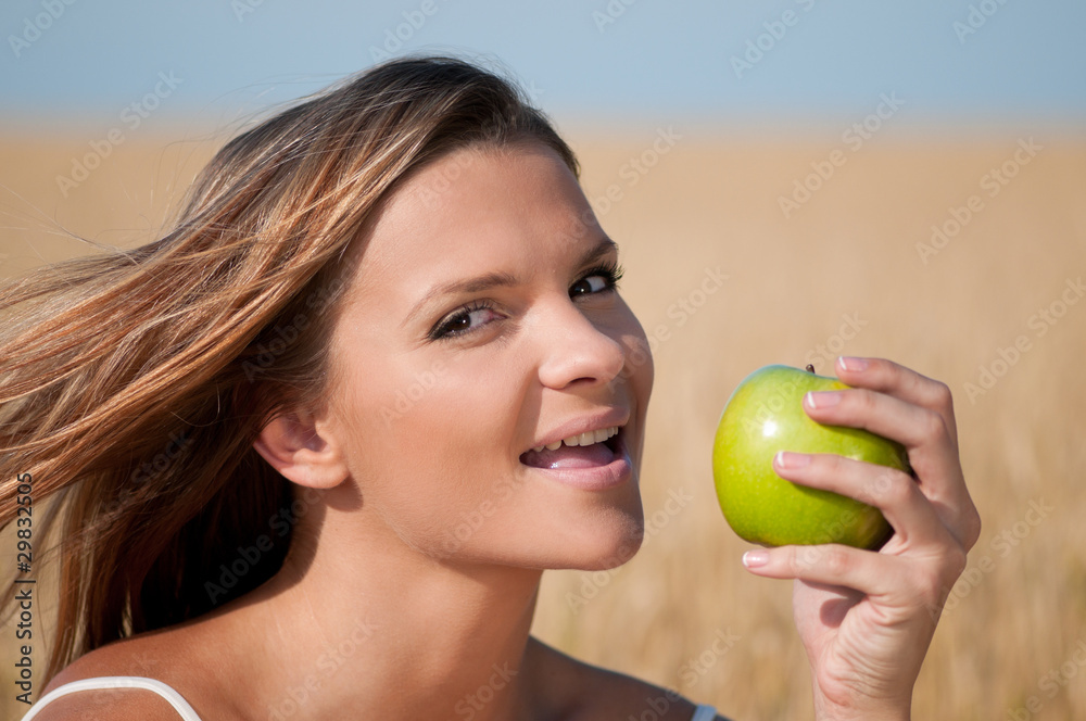 Woman in wheat field eating green apple. Summer picnic. Woman in wheat field eating green apple. Summer picnic.