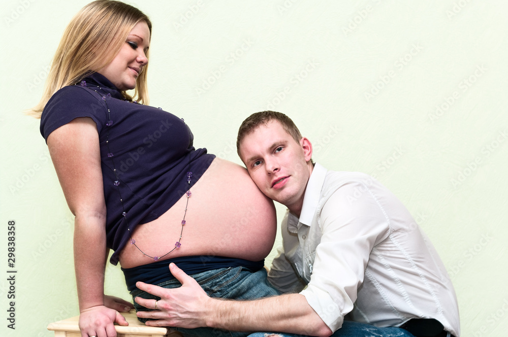 Pregnant woman with her husband hearing belly Pregnant woman with her husband hearing belly