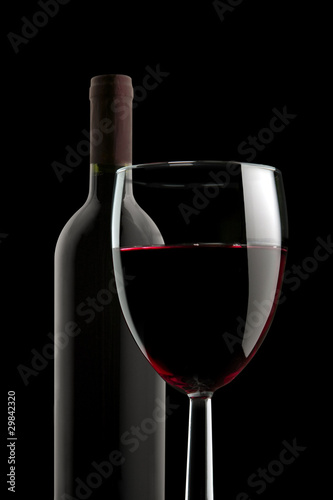 Glass of red wine and bottle on black background
